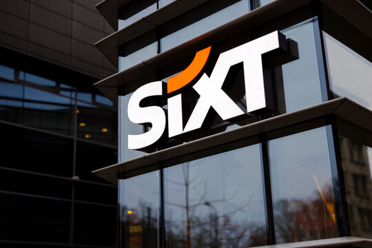 The logo of SIXT, an international car rental company, displayed on the facade of a modern glass office building. The image highlights corporate branding, business, and urban architecture.