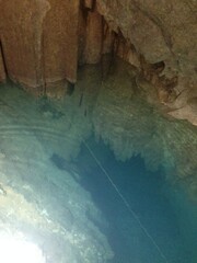 Crystal-Clear Underground Cave Pool in Japan; blue underground pool inside a natural cave in Japan, showing layered rock formations reflected in still water and soft light entering the cavern