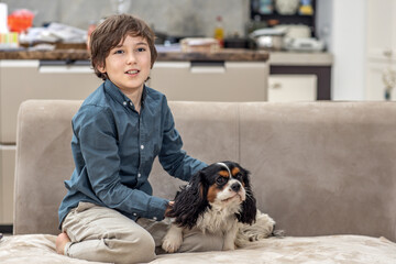Boy relaxing at home on sofa with his dog