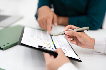 close up hand holding pen and pointing at  document .