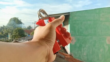 Hands doing hand exercises using handgrips outdoors.