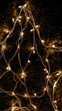 Vertical video: Moving camera reframing on gravel with wires, warm LED lights to show bulb nodes