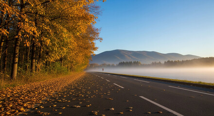 Scenic autumn road journey through misty mountains with vibrant fall foliage and fallen leaves, bathed in golden morning sunlight.