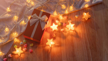 Red gift box and candlelight on a wooden table.