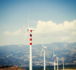 Wind turbines lined in a sunny mountain landscape, blending nature with clean energy.