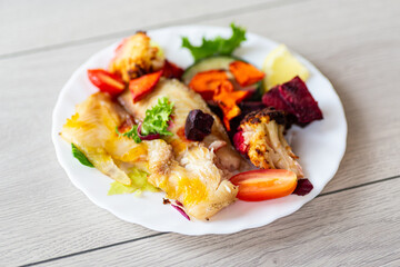 Gourmet baked fish meal with fresh vegetables and herbs