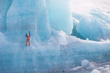 Climbers on a glacier in Iceland. A beautiful sunny winter day. A man climbing on a glacier in Iceland. They have a rope, ice axes, and crampons. Sunny day.