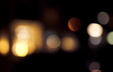 Softly diffused warm lights form abstract glowing shapes against a dark background, with golden