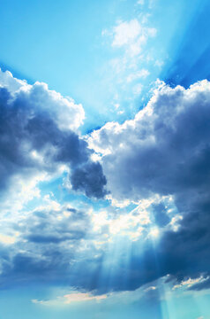 Sunbeams breaking through dramatic clouds on a bright blue sky