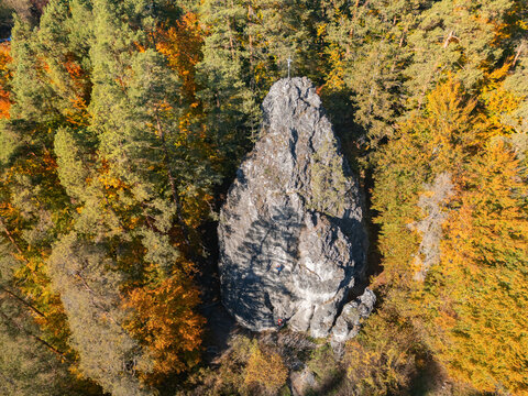 Aerial view of a massive rock formation shrouded by the vibrant hues of autumn trees, a symphony of greens, oranges, and yellows, Slovenska Lupca, Banskobystricky kraj, Slovakia.