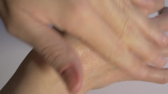 Close-up of hands applying moisturizing lotion, showcasing smooth skin texture and gradual absorption, with a gentle camera zoom in. Organic skincare concept