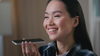 Asian Korean woman recording voice message talking speaker mobile phone ethnic Japanese girl female at home using virtual assistant smartphone app setting reminder indoor digital AI help technology