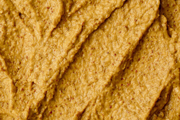 Mustard sauce with grains close-up. Hot spices as a background. Texture of Dijon mustard.