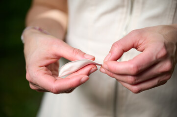 Crop view of the woman holding leaf in her hands looming magnolia flowers in spring garden, enjoying warm sunlight and nature. Peaceful lifestyle moment, outdoor leisure, mindfulness concept.