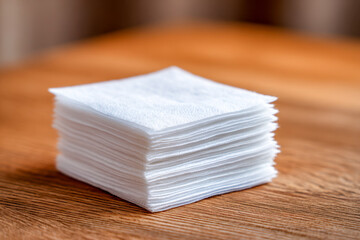 White folded tissue paper stack neatly arranged on wooden surface for cleaning and hygiene use in everyday life setting