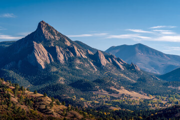 Scenic view of rugged rocky mountain peaks surrounded by forested slopes and a clear blue sky creating a peaceful natural landscape atmosphere