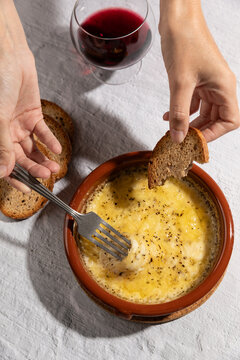 Female hand eating grilled provolone cheese with bread, argentinian provoleta.