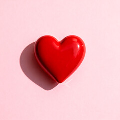 Obraz premium Minimalist close-up of a single red ceramic heart placed on a pale pink background with soft shadows. Clean studio setup, highly commercial, perfect for templates and banners.