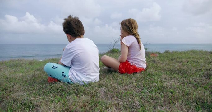 enfant de dos assis face &agrave; la mer en guadeloupe