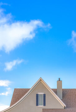 Roof with chimney of home against bright blue sky