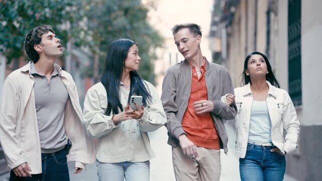 Four young multicultural friends enjoying a walk together. An asian woman is using her phone for directions while her companions are talking and looking around