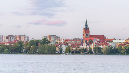 The city of Elk, landscape from the shore of Lake Elk showing the city buildings with the Catholic church, evening view over the water.