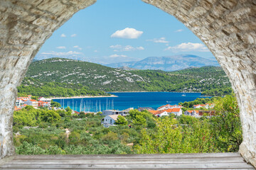 Croatian coastal landscape with green hills, blue water and a small town on the seashore, view of the mountain landscape on a sunny summer day.
