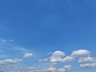 Clear blue sky with a few clouds. The sky is very bright and the clouds are scattered throughout in summer season. Copy space 