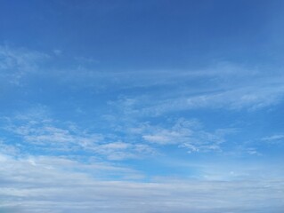Fototapeta premium Clear blue sky with a few clouds. The sky is very bright and the clouds are scattered throughout in summer season