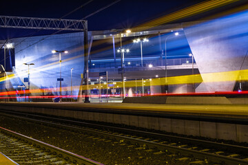 Obraz premium Train Light Trails At Modern Railway Station At Night, Suburban Public Transport And Mobility