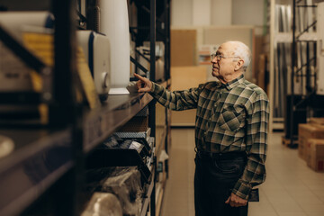 Fototapeta premium Senior man selecting products in hardware store aisle