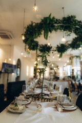 Wedding reception dinner table setting decorated with greenery