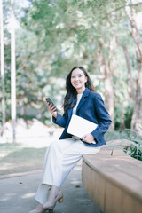 Naklejka premium Young Asian professional woman smiling with smartphone and laptop
