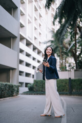 Fototapeta premium Asian businesswoman walking city street using smartphone
