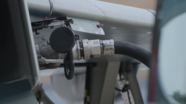 Military ground crew connecting service hose to fighter jet underside port for fueling or system servicing during pre flight ground operation to ensure safe and reliable mission readiness