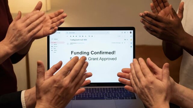 Brainstorming nonprofit grant approval funding celebration laptop screen with diverse hands clapping warm indoor setting showing appreciation