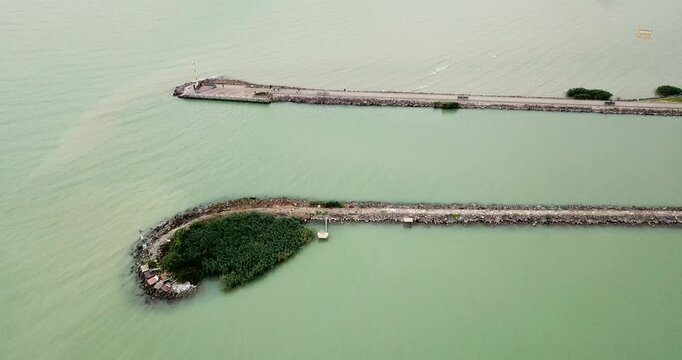 Aerial view of piers stretching into the still, green-tinted water of Lake Balaton, creating a tranquil scene of land meeting water, Fonyod, Hungary.