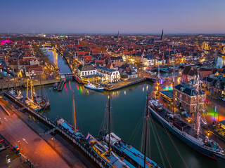 Fototapeta premium Aerial drone view of Harlingen harbour and illuminated waterfront at blue hour