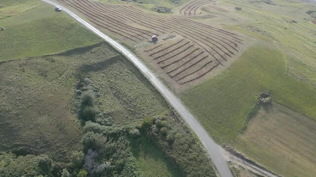 Drone footage of farmland near the coast. The camera highlights fields marked with lines of seaweed fertilizer and a parked tractor. Towards the end, a small section of coastline is visible.