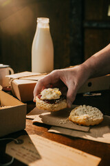 A person is holding a piece of toast with jam on it. A bottle of milk is next to the toast