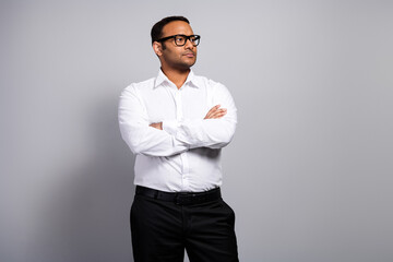 Young handsome business professional man standing in studio with arms crossed