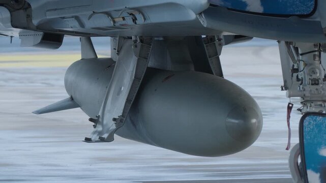 External fuel tank mounted under fighter jet fuselage to extend flight range and mission endurance during operational deployment