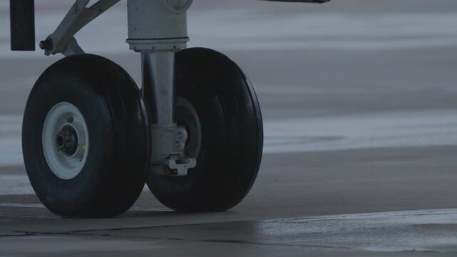 Aircraft landing gear wheels touching runway surface during landing sequence with motion blur and wet tarmac emphasizing aviation safety and transport