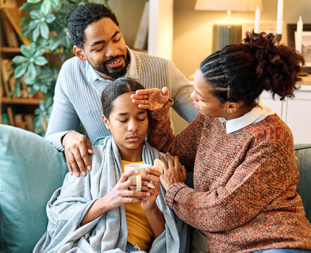 Portrait of a sick child teenager black girl with influenza virus fever or flu and worried parents mother and father, giving support and love to the child at home