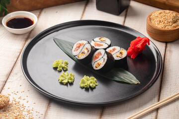 Yin yang sushi rolls with eel and salmon served on a black plate with wasabi and ginger © Hihitetlin