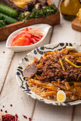 Traditional pilaf with tender meat, rice and vegetables served with fresh salad on a rustic wooden table