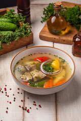 Traditional clear meat shorpa soup with potatoes carrots onion and fresh herbs served in a bowl on rustic table