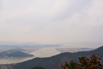 Obraz premium The view of the river and another mountain on a cloudy day from somewhere on the top of the mountain