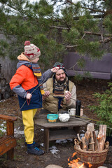 Father and son in winter clothes stringing marshmallows onto sticks for roasting outdoors