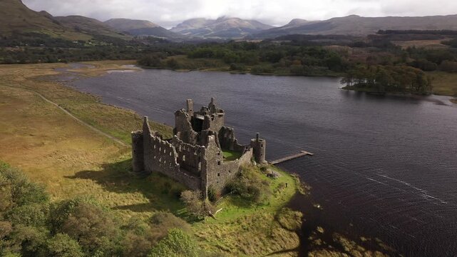 Aerial view of the majestic Kilchurn Castle ruins by the dark, rippled waters, surrounded by lush greenery, Dalmally, Scotland, United Kingdom.